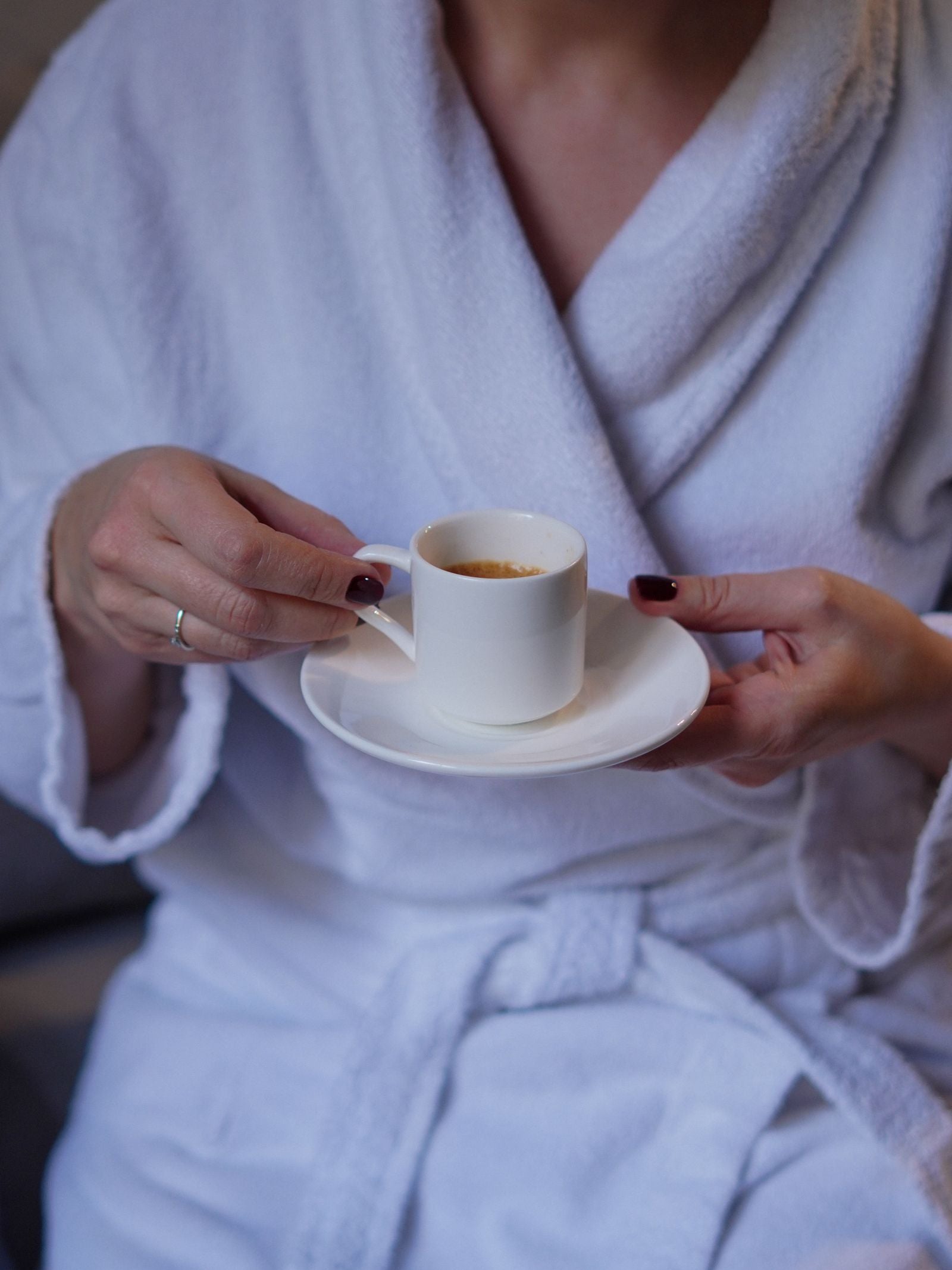 Hands holding an espresso cup on a saucer