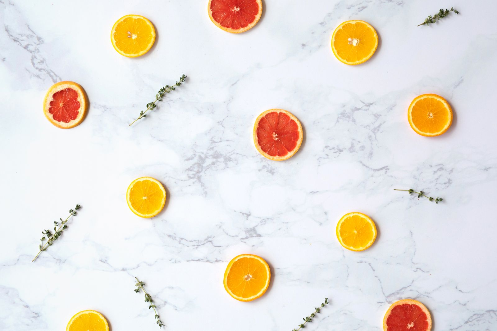 Orange and grapefruit slices with thyme on white marble